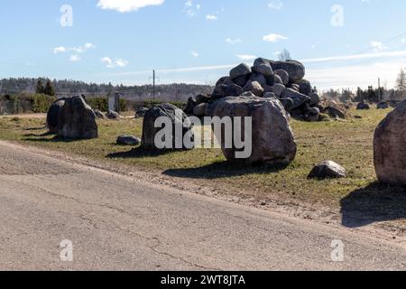 Grandi blocchi di pietra impilati sul lato di una strada di ghiaia e un mucchio di pietre sullo sfondo Foto Stock