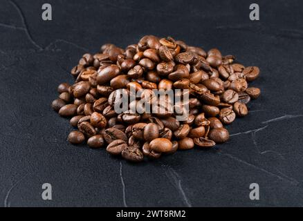 Piccola pila di chicchi di caffè arabica tostati primo piano su sfondo scuro Foto Stock