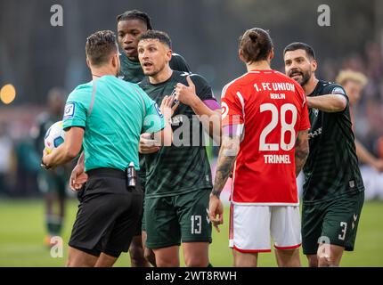 16 marzo 2024, Berlino: Calcio: Bundesliga, 1. FC Union Berlin - Werder Brema, Matchday 26, an der Alten Försterei. L'arbitro Daniel Schlager (l-r), Milos Veljkovic di Werder Brema, Christopher Trimmel di Berlino e Anthony Jung di Werder Brema discutono qualcosa sul campo. Foto: Andreas Gora/dpa - NOTA IMPORTANTE: In conformità con le normative della DFL German Football League e della DFB German Football Association, è vietato utilizzare o far utilizzare fotografie scattate nello stadio e/o della partita sotto forma di immagini sequenziali e/o serie di foto video. Foto Stock