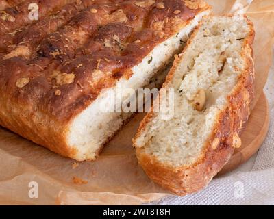 Pane caldo appena sfornato con formaggio e aglio, focalizzazione selettiva. Pane rustico a lievitazione naturale e una fetta tagliata Foto Stock