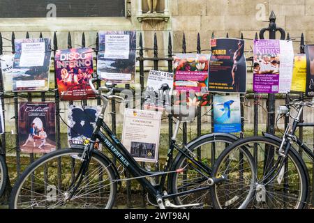 Biciclette appoggiate contro ringhiere con poster per concerti musicali a Cambridge. Foto Stock