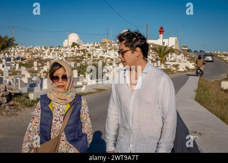 I turisti stranieri passeranno davanti al cimitero marittimo islamico di Mahdia e al faro di Mahdia, Borg Errass, Mahdia, Tunisia Foto Stock