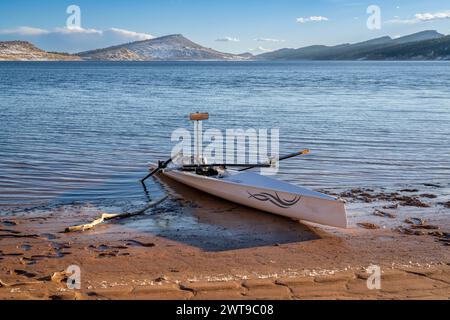 Loveland, CO, Stati Uniti d'America - 8 febbraio 2024: Conchiglia a remi costiera, Literace 1x di Liteboat, con specchio e borsa impermeabile sulla riva del lago Carter a Nor Foto Stock