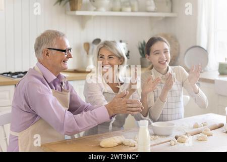 Famiglia multigenerazionale che ride, si diverte, scherza, cucina insieme Foto Stock