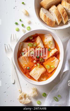 Primo piano di aringhe sottaceto con pomodori sott'olio su tavola bianca. Foto Stock