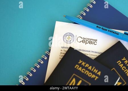 KIEV, UCRAINA - 27 NOVEMBRE 2023 logo del servizio passaporti con passaporto ucraino internazionale e penna sul tavolo Foto Stock