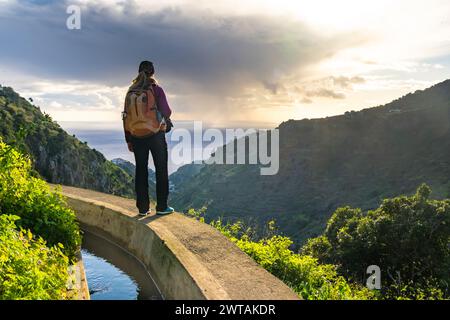 Turista a Levada do Norte sull'isola portoghese di Madeira. Canale di irrigazione di Levada. Escursioni a Madeira. Sentiero stretto vicino alla levada. Verde Foto Stock