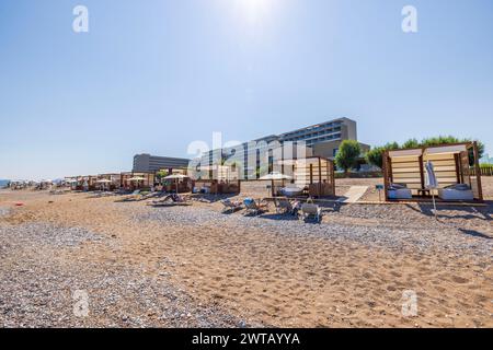 Splendida vista delle persone sulla spiaggia nel Mar Egeo con cabine individuali attrezzate sullo sfondo degli hotel. Rodi. Grecia. Foto Stock