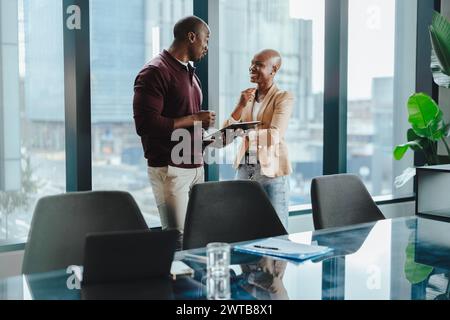Due professionisti collaborano e discutono idee in un ufficio moderno. Utilizzano un tablet durante la loro riunione di lavoro di successo. I felici colleghi d Foto Stock