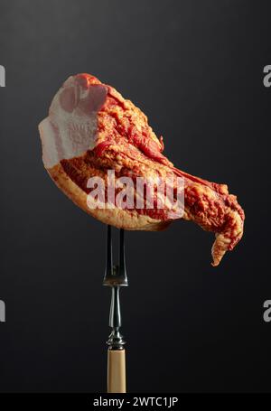 Un pezzo di maiale affumicato su una forchetta. Foto Stock