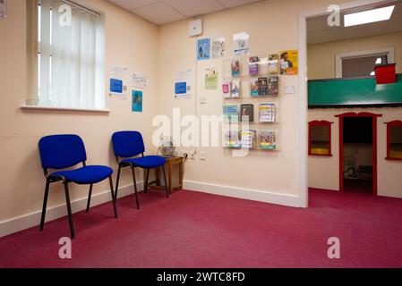 Una sala d'attesa dei medici con sedie, una casa wendy e un opuscolo Foto Stock