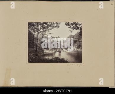 Cromwell's Bridge - Glengariffe. Probabilmente Sir John Joscelyn Coghill, fotografo (irlandese, 1826 - 1905) intorno al 1860-1870, Un giovane seduto sul bordo di una roccia che si affaccia su un fiume. Le rovine di un ponte di pietra ad arco attraversano il fiume di fronte a lui. Le pareti del ponte sono ricoperte di edera. (Recto, montaggio) in alto a destra, matita: "60"; in basso a destra, sotto l'immagine, matita: "Cromwell's Bridge - Glengariffe-"; Foto Stock