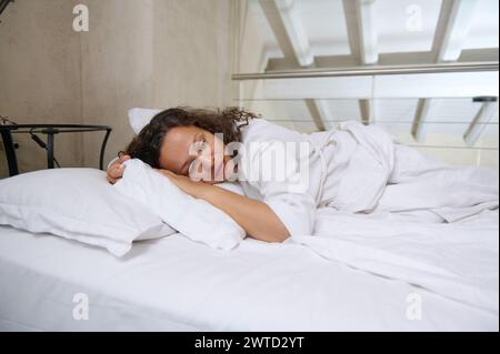 Donna di mezza età stressata sdraiata a letto a casa e piange. Donna infelice che soffre di tensione nervosa, disturbi emotivi, problemi psicologici, Foto Stock