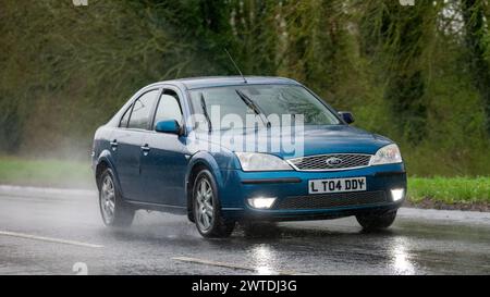 Milton Keynes, Regno Unito-17 marzo 2024: 2006 Ford Mondeo ghia auto diesel blu che guida sotto la pioggia Foto Stock