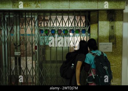 17 marzo 2024, Hong Kong, Cina: Le persone sbirciano all'interno di un negozio chiuso e vuoto presso la tenuta Tai Hang Sai. Costruita nel 1965, la tenuta di Tai Hang Sai è stata originariamente progettata per fornire alloggi ai residenti sfollati dall'autorizzazione dell'area di reinsediamento di Tai Hang Sai. Con oltre 1.600 unità a prezzi inferiori a quelli di mercato, è l'unica proprietà privata di Hong Kong. Attualmente sono in atto piani per demolire e riqualificare la tenuta, con il completamento stimato per il 2029. Si prevede che la riqualificazione fornisca più di 3.300 unità. (Immagine di credito: © Keith Tsuji/ZUMA Pre Foto Stock