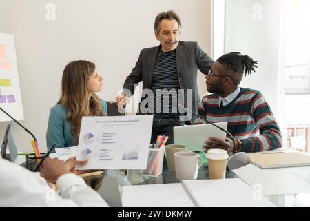 Team multiculturale impegnato nella discussione sull'analisi aziendale - una collaborazione vivace in un ufficio moderno - che illustra il lavoro di squadra e la pianificazione strategica Foto Stock