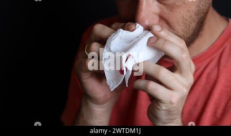 Uomo che tiene in mano un fazzoletto sanguinoso, primo piano Foto Stock