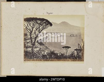 Napoli, pry du tombeau Virgile. Sconosciuto, fotografo 1861–1903 Vista dell'area del lungomare lungo le rive del Golfo di Napoli. Castel dell'Ovo, un complesso fortificato situato su una penisola sul Golfo, è visibile nell'area centrale destra dell'immagine, mentre il Vesuvio è visibile in lontananza. Questa vista è vista da un punto panoramico elevato, parzialmente oscurato da arbusti e pini di pietra. (Recto, Mount) centro superiore, in inchiostro viola: "Napoli"; Foto Stock