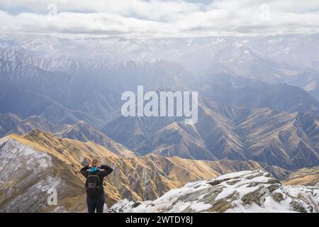 Escursionista donna in piedi sulla cima della montagna godendo di vedute sulle catene montuose di fronte a lei Foto Stock