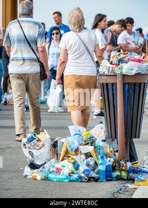 Bucarest, Romania - 16 settembre 2023: Bidone della spazzatura pieno di spazzatura. Traboccante di rifiuti con molte persone intorno. Concetto ambientale. Foto Stock