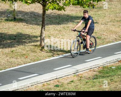 Bucarest, Romania - 16 settembre 2023: Giovane adulto in bicicletta sulla nuova pista ciclabile intorno al lago Dambovita (Lacul Morii), a Bucarest. Foto Stock