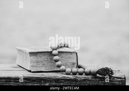 Un vecchio libro e un rosario di legno giacciono sulle panchine dei parchi in Ucraina, fede e religione, pregate Foto Stock