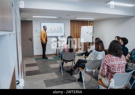 Presentazione coinvolgente in ufficio. Giovane uomo d'affari nero che guida la formazione aziendale. Foto Stock