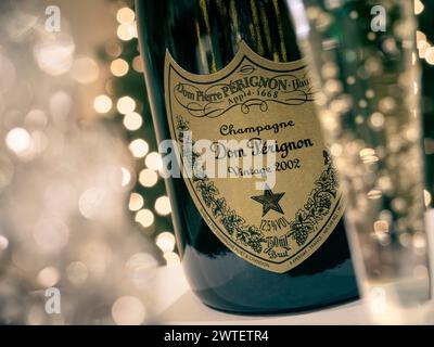 DOM PERIGNON retrò in stile vintage. Bottiglia e flauto appena versato di fine vendemmia 2002 Dom Perignon, champagne francese di lusso rinomato con scintillanti luci da festa alle spalle. Foto Stock