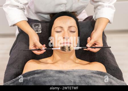Estetista che applica cosmetici al cliente nel centro estetico Foto Stock