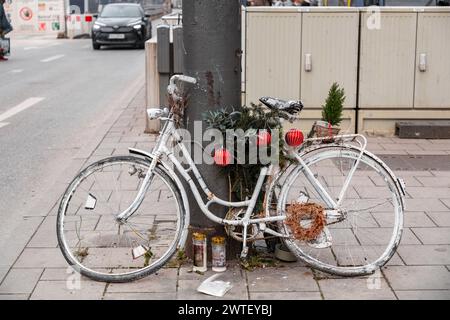 Monaco di Baviera, Germania - 23 dicembre 2021: Bicicletta abbandonata vecchia e obsoleta dipinta di bianco con decorazioni natalizie in una strada a Monaco, Germania Foto Stock