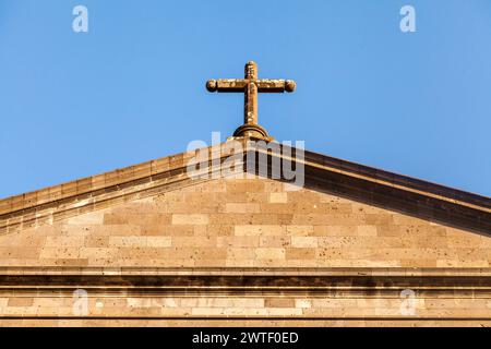 In cima al tetto di una chiesa cattolica con croce contro il cielo blu Foto Stock