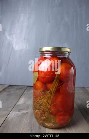 Cibo in scatola. Pomodori salati in un vasetto di vetro su sfondo grigio con spazio per testo foto verticale Foto Stock