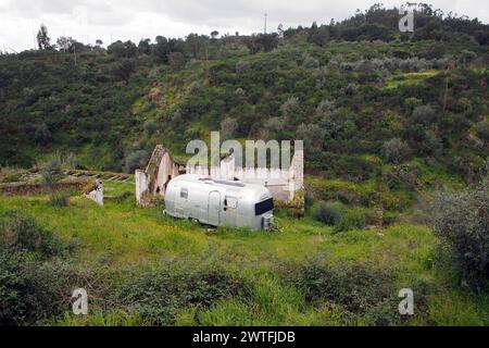 Rimorchio residenziale vecchio stile parcheggiato sul verde accanto alla casa rurale in rovina, sullo sfondo di un paesaggio collinare, vicino a Belver, Portogallo Foto Stock