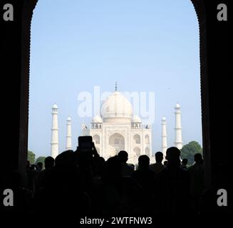 Silhouette di turisti che scattano foto con i telefoni all'ingresso principale del Taj Mahal Foto Stock