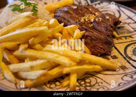 Bistecca alla griglia con patatine fritte e riso su un piatto in un ristorante. Stile portoghese. Messa a fuoco selettiva. Foto Stock