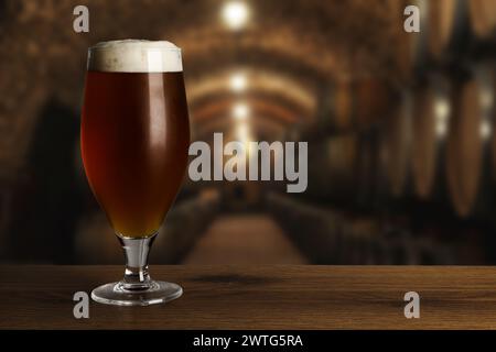 Bicchiere con birra fresca su un tavolo di legno in cantina, spazio per testo Foto Stock