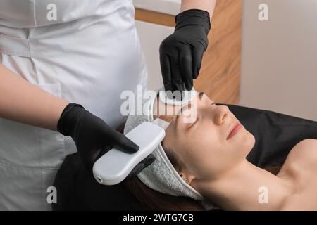 Cosmetologo che utilizza lo scrubber a ultrasuoni, primo piano. Cliente con procedura di pulizia in clinica Foto Stock