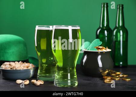 St La festa di Patrick. Birra verde, cappello di leprechaun, vaso d'oro e pistacchi su un tavolo di legno Foto Stock
