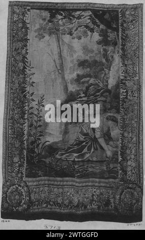 Toilette di Venere (Afrodite). Vouet, Simon (francese, 1590-1649) (progettato dopo, attr.) [Pittore] c. 1640 arazzi dimensioni: H 9'8' x W 6'7' arazzo materiali/tecniche: Cultura sconosciuta: French Weaving Center: Paris Ownership History: French & Co. (?). In un ambiente boscoso, la donna inginocchiata tiene i nastri in mano (BRD) ghirlanda floreale; cesti incorniciati da ghirlande negli angoli inferiori; fascia stretta esterna con guilloche a spirale frammento di arazzo; sinistra 1/3 della composizione originale. Nella composizione originale, il piede di Venere appare direttamente sotto le mani dell'assistente, che sta legando i nastri o Foto Stock