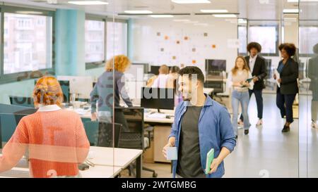 Colleghi che arrivano in ufficio e si siedono sulla scrivania Foto Stock