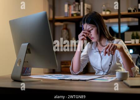 La giovane donna lavora a casa fino a tardi Foto Stock