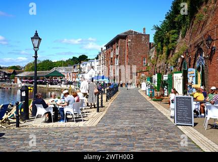 I turisti seduti nei caffè sul marciapiede lungo la banchina est del fiume exe, Exeter, Devon, Regno Unito, Europa. Foto Stock