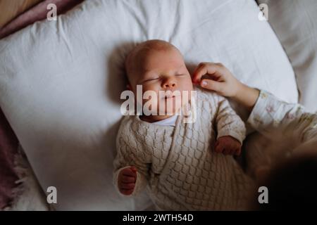 Vista dall'alto del bambino che dorme nel letto, la sorella maggiore che accarezza la guancia del neonato. Amore fraterno, gioia per un nuovo membro della famiglia. Foto Stock