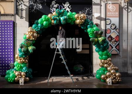 Gli appaltatori installano balloni verdi shamrock ispirati al giorno di San Patrizio sulla porta di un locale del West End prima delle celebrazioni irlandesi del fine settimana, il 15 marzo 2024, a Londra, Inghilterra. I cugini Sachin e Vivek gestiscono "Festive Floats London", una festa su misura e un evento in mongolfiera dalla parte est di Londra. Foto Stock