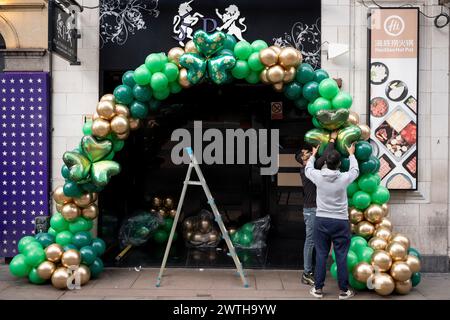 Gli appaltatori installano balloni verdi shamrock ispirati al giorno di San Patrizio sulla porta di un locale del West End prima delle celebrazioni irlandesi del fine settimana, il 15 marzo 2024, a Londra, Inghilterra. I cugini Sachin e Vivek gestiscono "Festive Floats London", una festa su misura e un evento in mongolfiera dalla parte est di Londra. Foto Stock