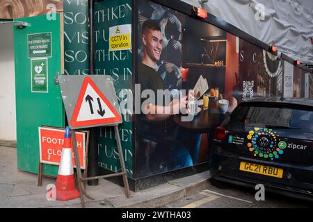 Un accumulo di costruzioni mostra stili di vita aspirazioni accanto a una Zipcar parcheggiata nel West End, il 15 marzo 2024, a Londra, Inghilterra. Foto Stock