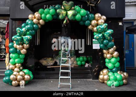 Gli appaltatori installano balloni verdi shamrock ispirati al giorno di San Patrizio sulla porta di un locale del West End prima delle celebrazioni irlandesi del fine settimana, il 15 marzo 2024, a Londra, Inghilterra. I cugini Sachin e Vivek gestiscono "Festive Floats London", una festa su misura e un evento in mongolfiera dalla parte est di Londra. Foto Stock