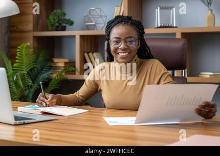 Un freelance professionista soddisfatto con dreadlock lavora da casa Foto Stock
