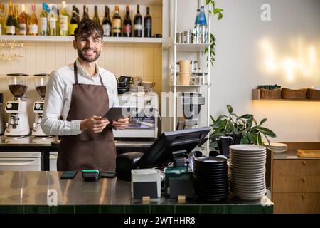 Barman barman barman in piedi con un tablet digitale al bancone del bar Foto Stock