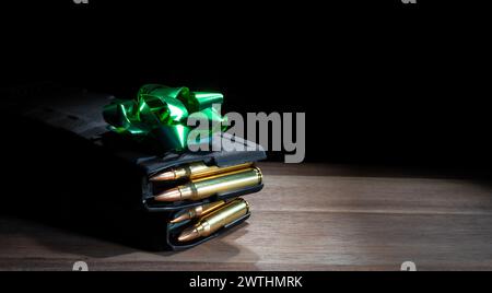 Prua verde sopra due caricatori AR-15 ad alta capacità caricati su un tavolo come regalo per il proprietario di una pistola. Foto Stock